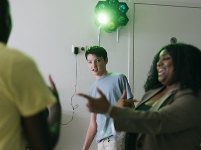 Een jongen en een vrouw zijn aan het dansen. Achter hen aan de muur hangt een discolamp.