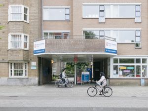Een gebouw met drie verdiepingen met een brede ingang door het gebouw heen. Daarboven staat een bord met 'Nieuw Vredenburgh', het logo van Cordaan en een pijl en tekst 'St. Augustinuskerk'.