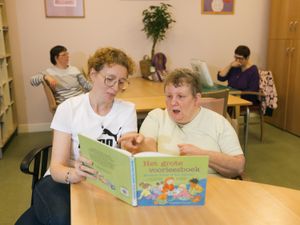 Twee vrouwen met kort haar lezen samen in 'het grote voorleesboek'.