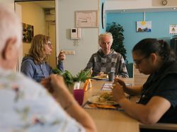 4 bewoners eten samen aan tafel in de gezamenlijke woonkamer