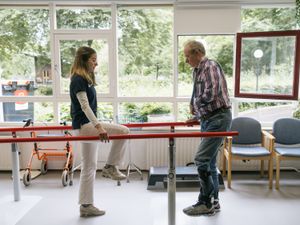 Een man en een fysiotherapeut doen oefeningen op de loopbrug.