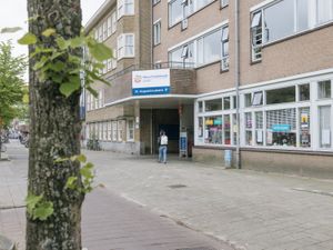 Een gebouw met drie verdiepingen met een brede ingang door het gebouw heen. Daarboven staat een bord met 'Nieuw Vredenburgh', het logo van Cordaan en een pijl en tekst 'St. Augustinuskerk'.