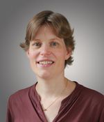 Een vrouw met kort haar kijkt vriendelijk in de camera