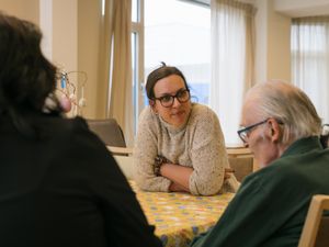 Persoon luistert aandachtig naar andere persoon aan tafel