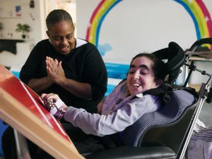 Een persoon in een rolstoel heeft bandje om de hand dat geluid maakt als die er mee beweegt en maakt samen met iemand die in haar handen klapt muziek