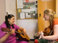 2 personen kijken elkaar lachend aan en spelen gitaar