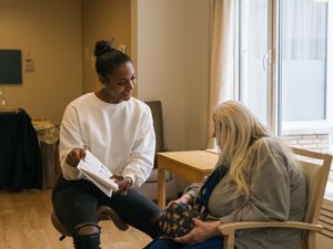 1 persoon helpt een ander persoon met een boekje te lezen