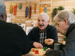 Ouderen spelen aan tafel een spelletje en lachen samen