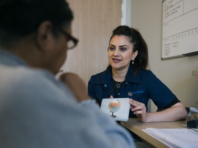 Een vrouw met lang donker haar hout een papiertje vast met een wereldbol erop. De andere persoon kijkt ernaar.
