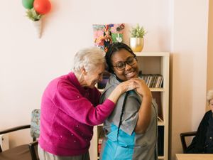 Medewerkster en oudere dame dansen en lachen samen