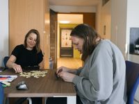 2 personen zitten aan tafel een spelletje te doen