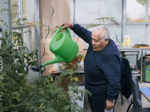 1 persoon is met een groene gieter de planten aan het watergeven