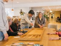 Een groep bewoners en medewerkers zijn aan het sjoelen