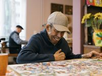 Oudere man met pet maakt een legpuzzel