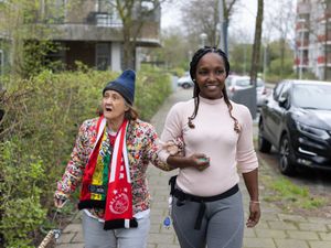 Twee personen wandelen gearmd op de stoep en kijken om zich heen