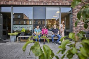 Vier mensen zitten gezellig buiten op een bankje bij Clubhuis Noord. Ze genieten van het zonnetje.