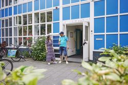 Een geanimeerd gesprek tussen een begeleider en een deelnemer voor de ingang van Centrum Kijkduin.