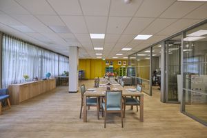 Een eetzaal met een lange gedekte tafel, glazen wanden scheiden de ruimte.