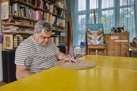 Een deelnemer aan dagbesteding is geconcentreerd bezig om met een figuurzaag een houten plank te zagen.