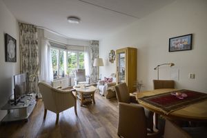 Een woning ingericht met een zithoek en een eettafel, ook staat er een televisie.