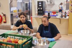 Twee vrouwen zitten aan tafel in de keuken appels te schillen.