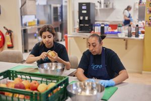 Twee vrouwen zitten aan tafel in de keuken appels te schillen.