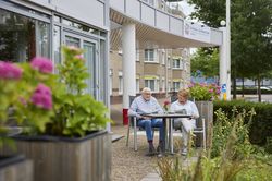 Twee mensen drinken koffie aan een tafel in de tuin.