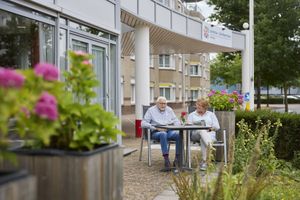 Twee mensen drinken koffie aan een tafel in de tuin.
