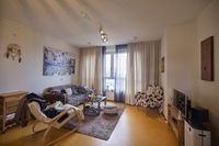 Een zithoek in een appartement met meubels met allerlei verschillende prints. Aan de muur hangt een schilderij van een stad.