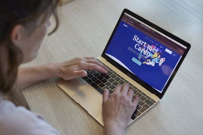 Een persoon achter een laptop waarop een website is geopend met de tekst Start met Caren.