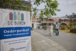 Een begeleider en deelnemer lopen met soepele tred naar de tuin om de planten en bloemen water te geven. Want het is vandaag lekker zonnig buiten.