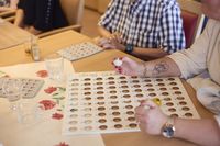 Een begeleider leidt een spelletje bingo, het bord waar de balletjes op komen te liggen, lig voor haar.