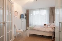 Een slaapkamer in een seniorenwoning van Beth Shalom met een stoel en eettafel