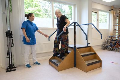 Medewerker helpt cliënt oefenen met traplopen