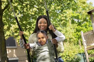 Kind op de schommel en begeleider erachter lachen samen
