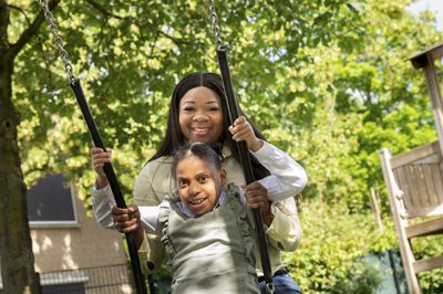 Kind op de schommel en begeleider erachter lachen samen