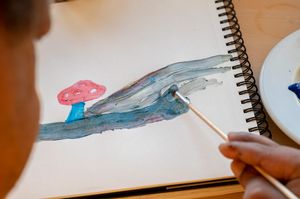 Iemand schildert een paddenstoel in een schetsboek.