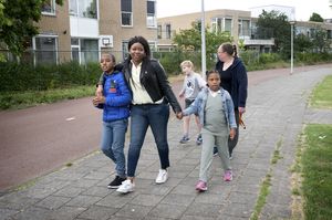 Drie kinderen en twee begeleiders wandelen op straat hand in hand