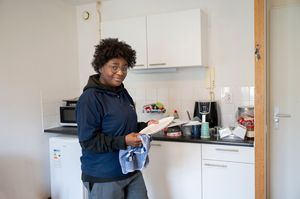 Persoon met bril op is in keuken een bord aan het afdrogen met een theedoek