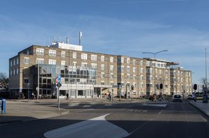 Langwerpig gebouw, 5 etages van lichte baksteen met glazen entree.