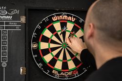Persoon haalt de dartpijlen uit het dartbord
