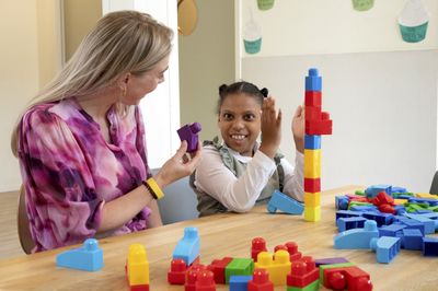 Kind en begeleider bouwen een blokkentoren en het kind klapt