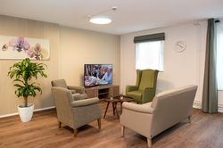 Sfeervolle woonkamer met houten laminaatvloer en lichte meubels en een tv.