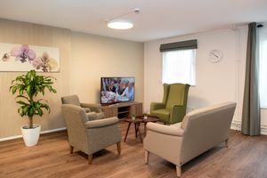 Sfeervolle woonkamer met houten laminaatvloer en lichte meubels en een tv.