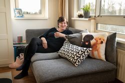 Persoon in woonkamer hangt ontspannen op loungebank met kussens met verschillende opdruk