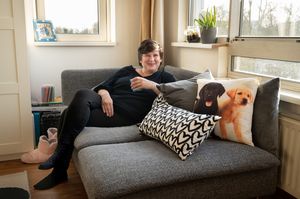 Persoon in woonkamer hangt ontspannen op loungebank met kussens met verschillende opdruk