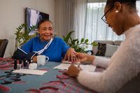 Medewerker lakt nagels van cliënt aan tafel