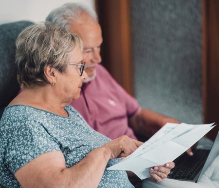 Een mantelzorger helpt haar man met de administratie.