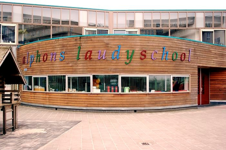 Ingang gebouw speciaal onderwijs Alphons Laudy School. Houten gevel met kleurrijke letters en ramen.