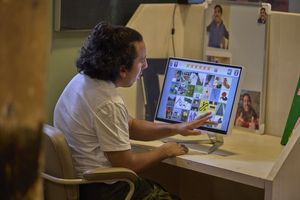 een man zit aan een bureau voor een computer met touch screen.